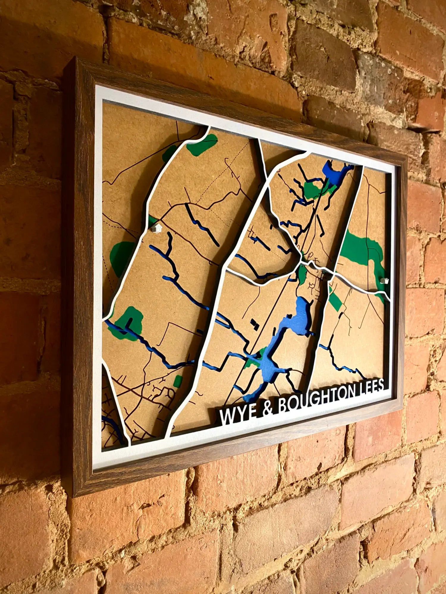 a framed wooden map on a wall with Wye and Boughton Aluph on the map