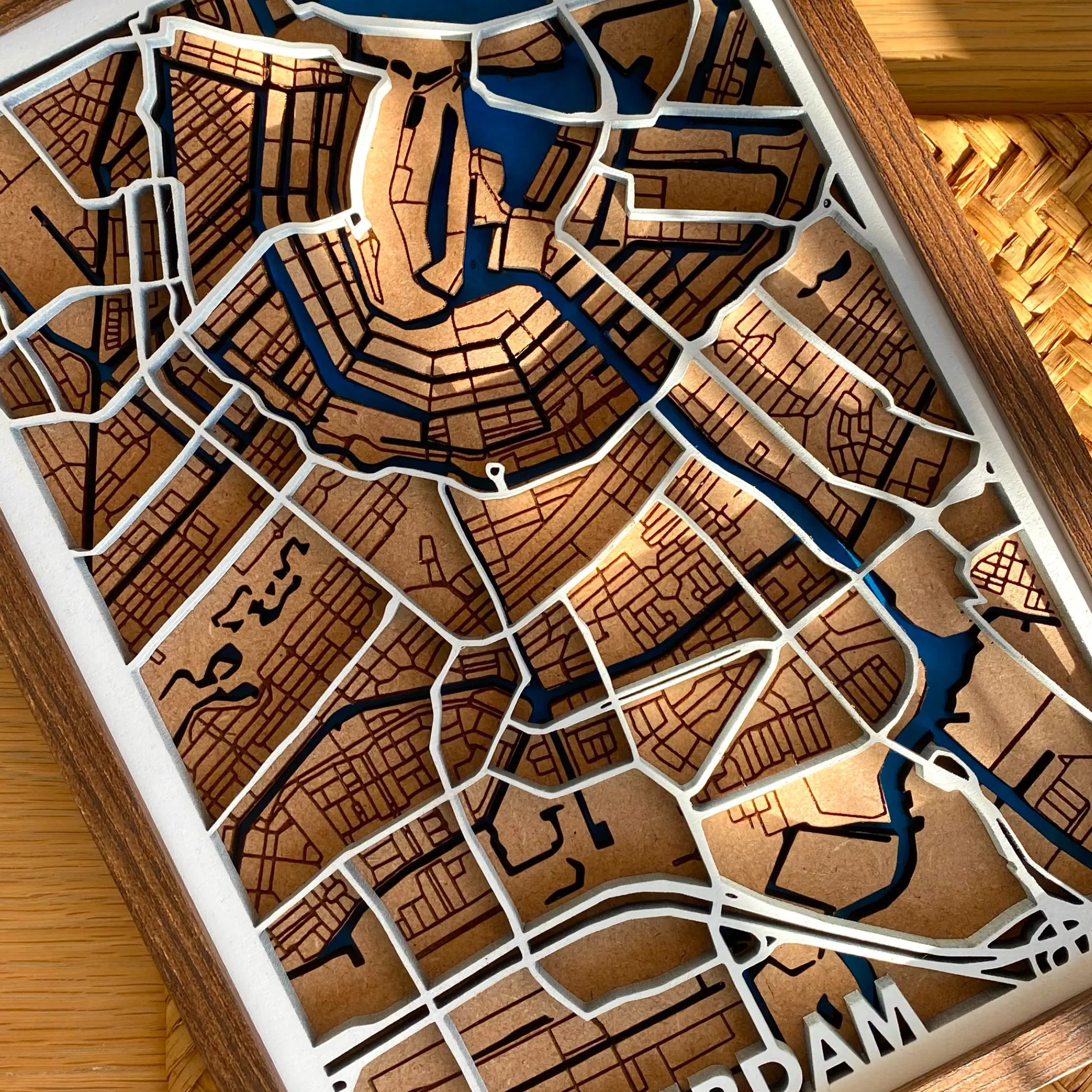 A closer look at the 3D laser-cut MDF letters of AMSTERDAM that are hand-painted in white on the bottom left hand corner of the frame. These letters are 3D and connect with the main roads/motorways layer of the wooden map.